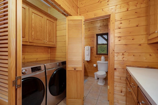 washroom with cabinets, wooden walls, light tile patterned flooring, and separate washer and dryer