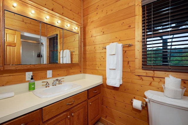 bathroom featuring vanity, wood walls, toilet, and a shower with door