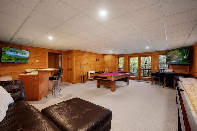 rec room with a paneled ceiling, light carpet, wooden walls, indoor bar, and billiards