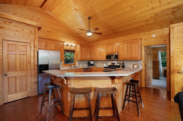 kitchen featuring appliances with stainless steel finishes, wood walls, high vaulted ceiling, and hardwood / wood-style flooring