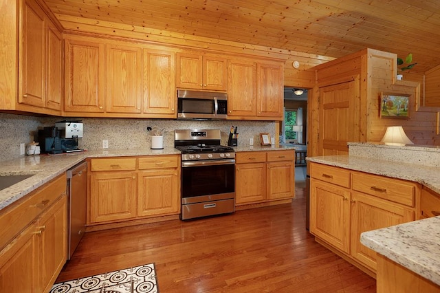 kitchen with appliances with stainless steel finishes, wood ceiling, light wood-type flooring, and light stone countertops