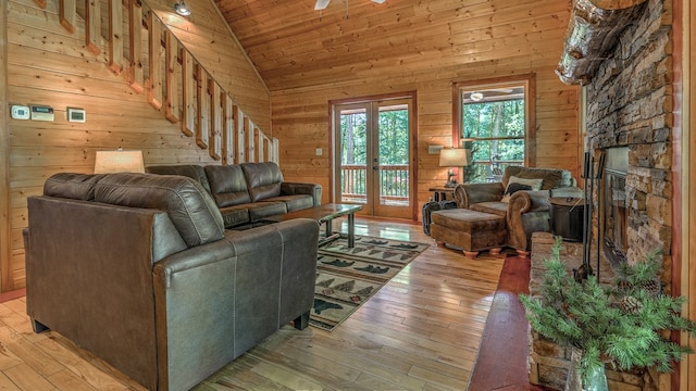 living room featuring wooden walls, a stone fireplace, light hardwood / wood-style flooring, and wooden ceiling