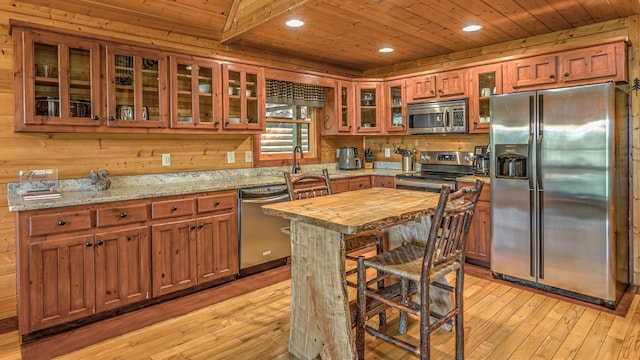 kitchen featuring wood ceiling, appliances with stainless steel finishes, light hardwood / wood-style floors, and light stone counters