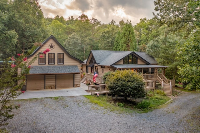 view of front of home featuring roof with shingles, a view of trees, a garage, driveway, and stairs