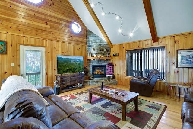 living room with wooden walls, high vaulted ceiling, beam ceiling, a fireplace, and light hardwood / wood-style flooring