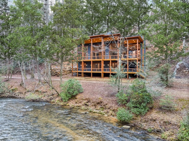 back of property with a view of trees and a deck with water view