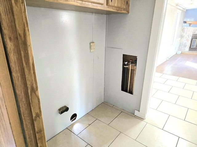 laundry room featuring light tile patterned floors and a stone fireplace