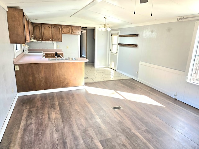 kitchen featuring lofted ceiling, sink, hardwood / wood-style flooring, decorative light fixtures, and kitchen peninsula