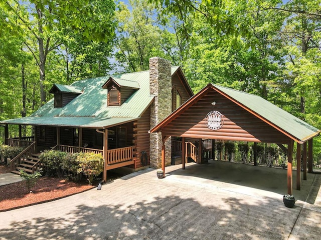 log home with covered porch and a carport