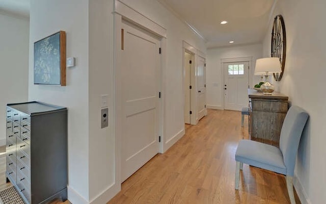 hallway with light hardwood / wood-style floors and ornamental molding