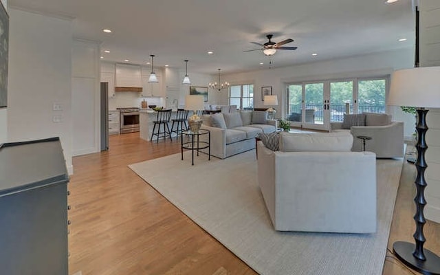 living room with ceiling fan with notable chandelier, light wood-type flooring, and french doors