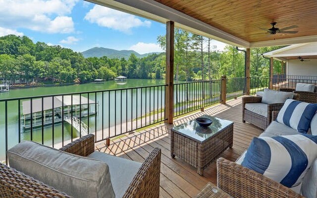 deck featuring an outdoor living space, ceiling fan, and a water and mountain view