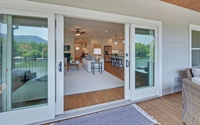 doorway to outside featuring a fireplace, hardwood / wood-style floors, ceiling fan, and a healthy amount of sunlight