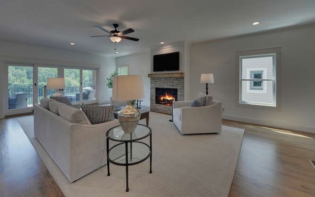 living room featuring ceiling fan, light hardwood / wood-style floors, and a fireplace