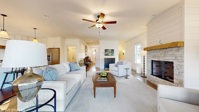 living room featuring a fireplace, light hardwood / wood-style floors, ceiling fan, and crown molding