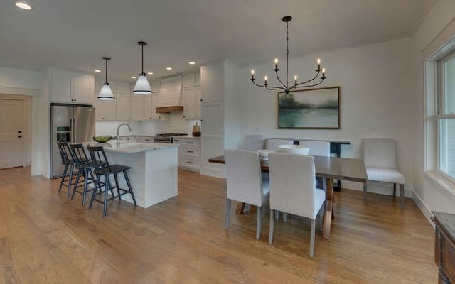 kitchen with appliances with stainless steel finishes, white cabinetry, hanging light fixtures, and custom exhaust hood