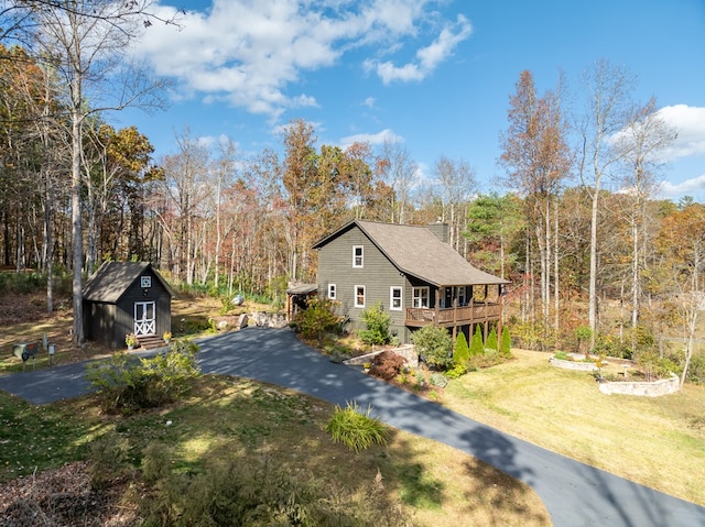 view of side of property featuring a yard, a deck, and a shed