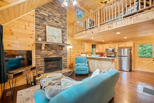 living room with hardwood / wood-style flooring, wooden ceiling, a fireplace, and wood walls