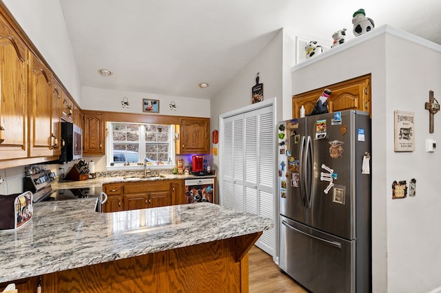 kitchen featuring kitchen peninsula, sink, stainless steel appliances, and lofted ceiling