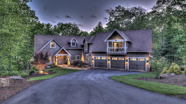 craftsman-style home featuring stone siding, driveway, an attached garage, and roof with shingles