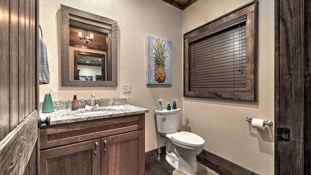 half bath featuring toilet, baseboards, wood finished floors, and vanity