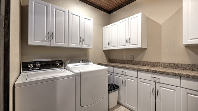 washroom featuring cabinet space, wooden ceiling, washer and clothes dryer, and a textured wall