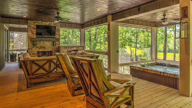 sunroom / solarium with a stone fireplace and ceiling fan