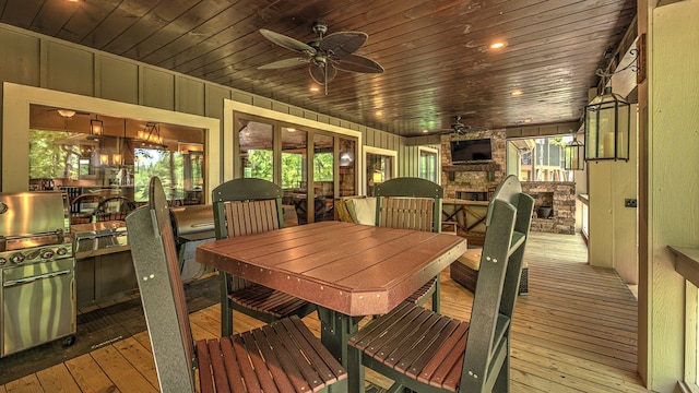 dining space featuring hardwood / wood-style floors, ceiling fan, wooden walls, wood ceiling, and a stone fireplace