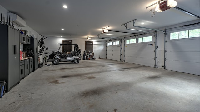 garage featuring a garage door opener, a wall mounted AC, and recessed lighting
