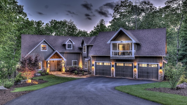 craftsman-style house featuring roof with shingles, a garage, stone siding, and driveway