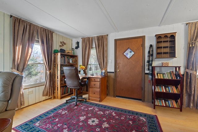 home office featuring light hardwood / wood-style flooring and wood walls