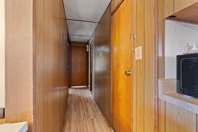 corridor featuring light hardwood / wood-style flooring and wood walls