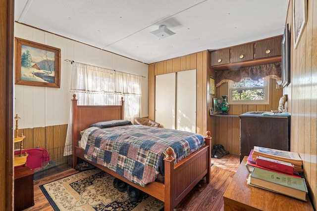 bedroom featuring wooden walls and dark hardwood / wood-style floors