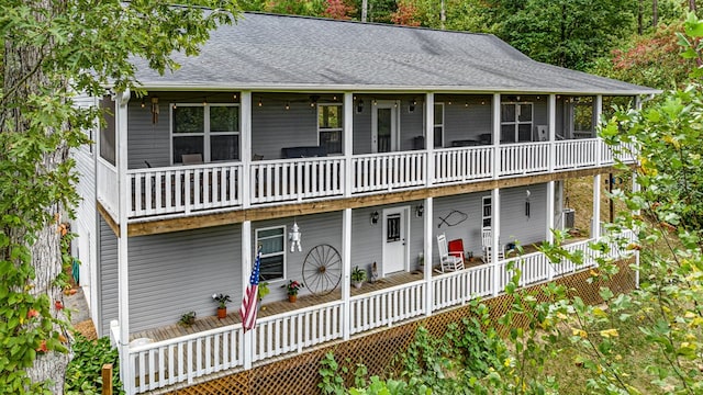 view of front of property featuring roof with shingles, a deck, and a sunroom