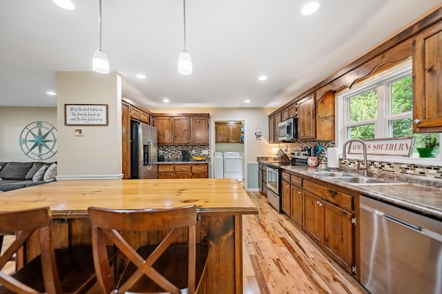 kitchen featuring stainless steel appliances, separate washer and dryer, a sink, recessed lighting, and tasteful backsplash