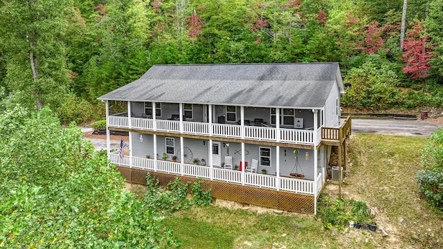 rear view of property with a forest view, cooling unit, and a deck