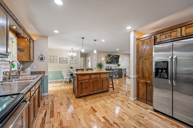 kitchen with stainless steel refrigerator with ice dispenser, a sink, a center island, light wood-type flooring, and a chandelier