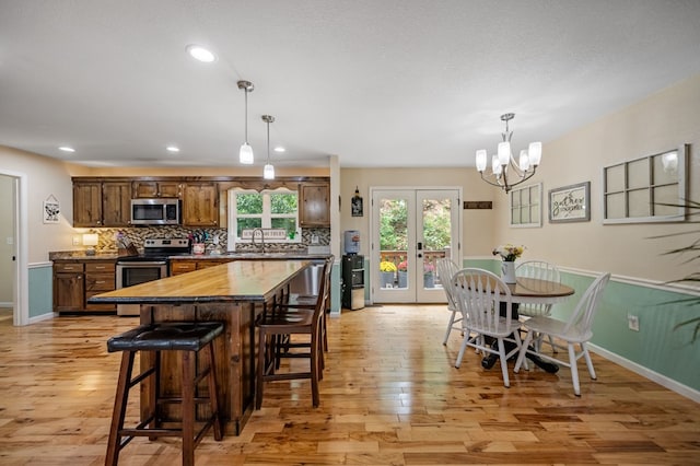kitchen featuring appliances with stainless steel finishes, light wood-style flooring, a kitchen breakfast bar, decorative backsplash, and recessed lighting