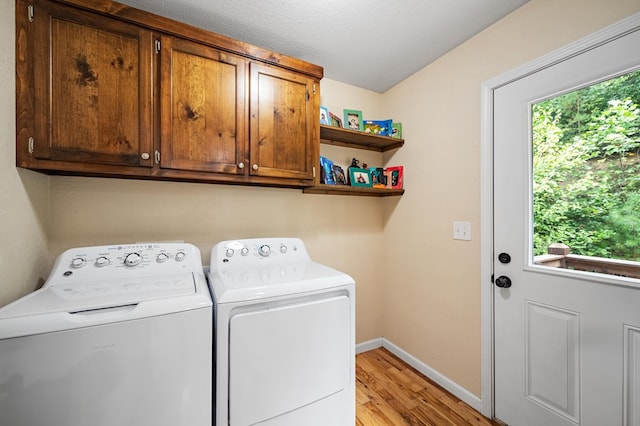 washroom featuring washer and clothes dryer, light wood finished floors, cabinet space, and plenty of natural light