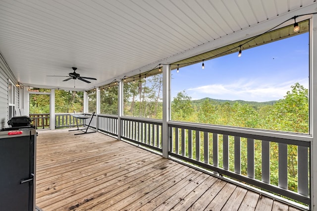 wooden terrace featuring ceiling fan and a forest view