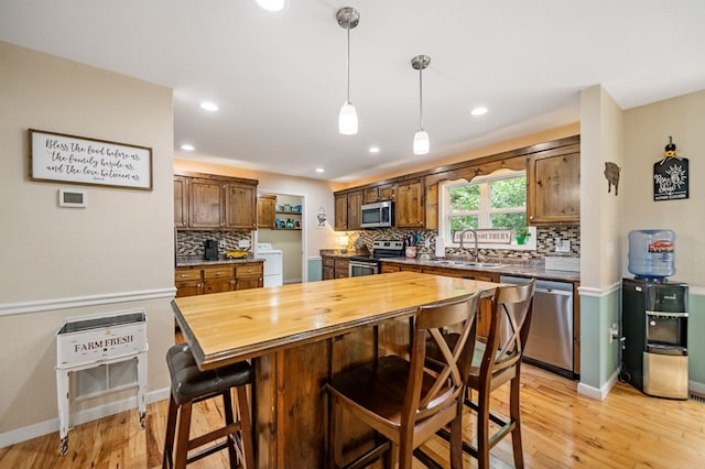 kitchen featuring stainless steel appliances, separate washer and dryer, wooden counters, a sink, and a kitchen breakfast bar
