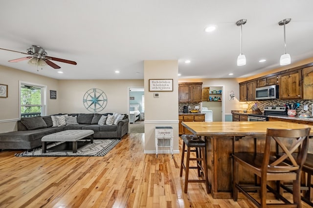 kitchen with appliances with stainless steel finishes, butcher block counters, a breakfast bar area, light wood-style flooring, and recessed lighting