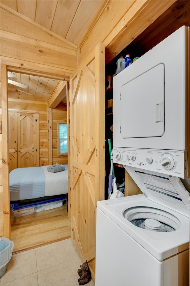 washroom with wooden ceiling, light tile patterned floors, stacked washer / drying machine, and wooden walls