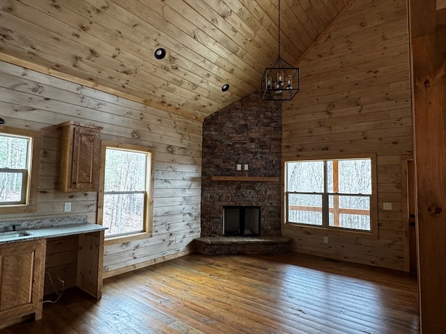 kitchen featuring a fireplace, decorative light fixtures, wood walls, hardwood / wood-style flooring, and wooden ceiling