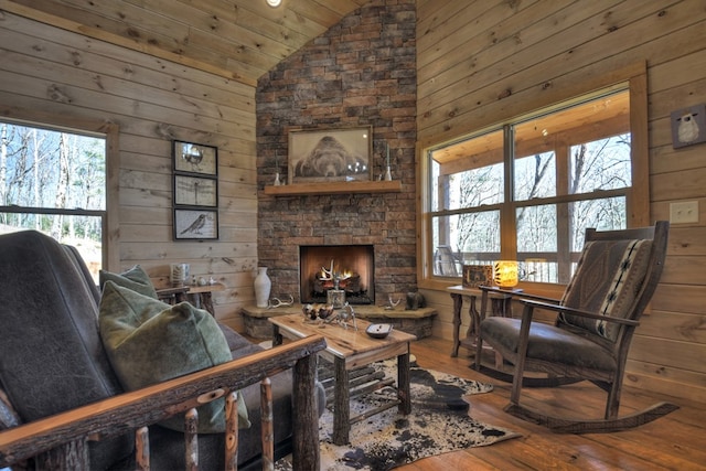 living room with hardwood / wood-style floors, high vaulted ceiling, a fireplace, wooden ceiling, and wood walls