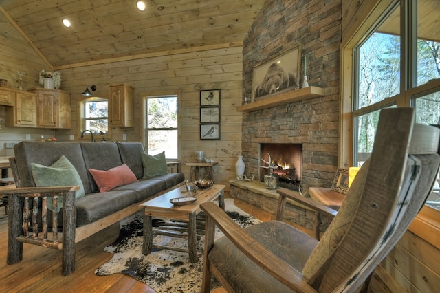 living room featuring lofted ceiling, a stone fireplace, wooden ceiling, wooden walls, and hardwood / wood-style floors