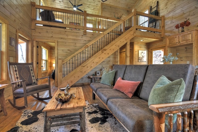 living room featuring wood ceiling, ceiling fan, a high ceiling, wood-type flooring, and wood walls