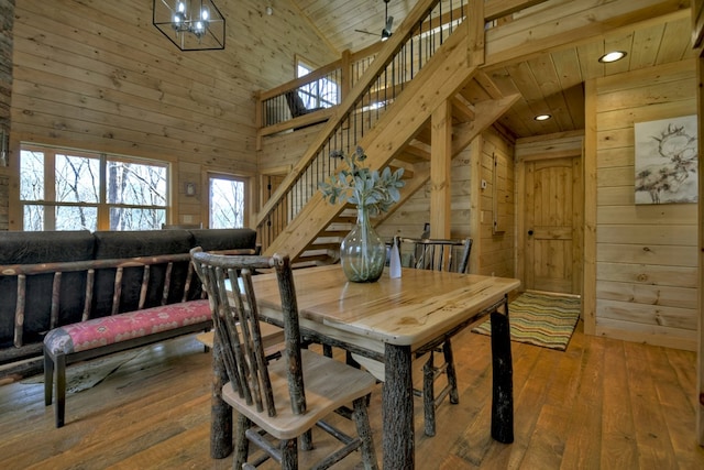 dining space featuring wood ceiling, wood-type flooring, a high ceiling, and wood walls