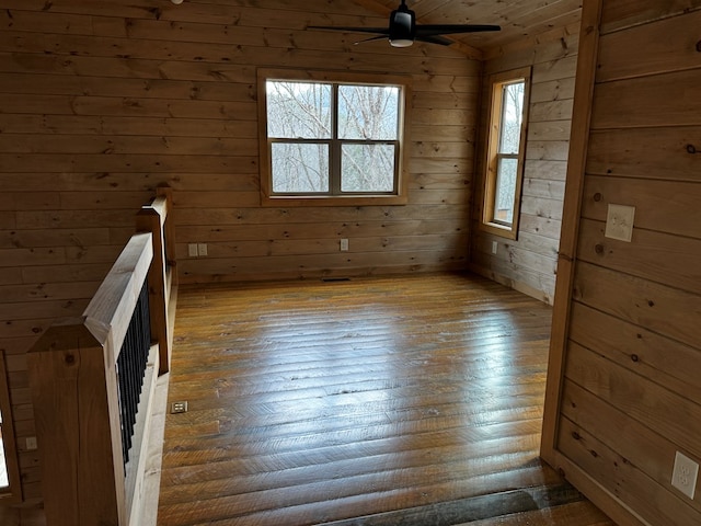 empty room featuring lofted ceiling, ceiling fan, and wood walls