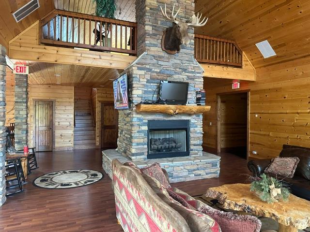 405 Lola Dr, Blairsville, GA 30512 - living room with wood ceiling, wood walls, wood finished floors, a stone fireplace, and high vaulted ceiling
